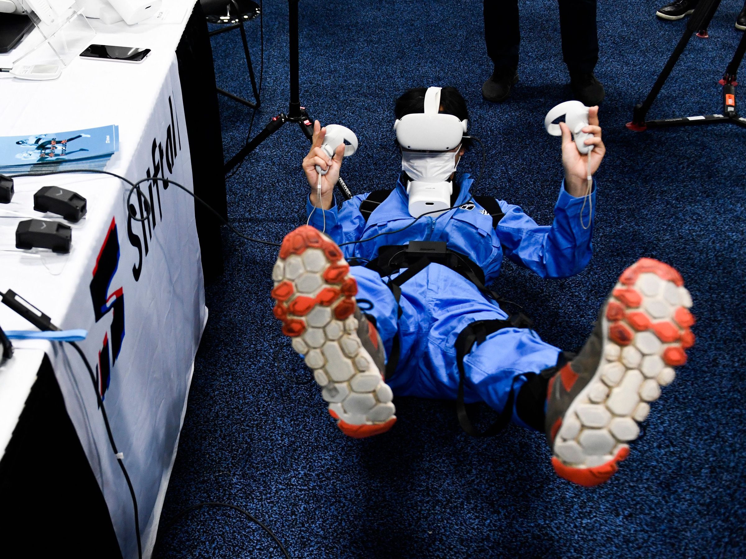 A CES attendee lies on the floor for a metaverse experiences while wearing an Oculus headset.